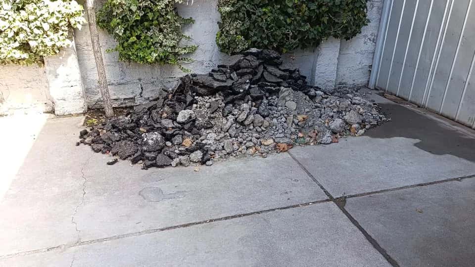 Antes del retiro de escombros en patio adoquinado con hiedra y material acumulado en Santiago